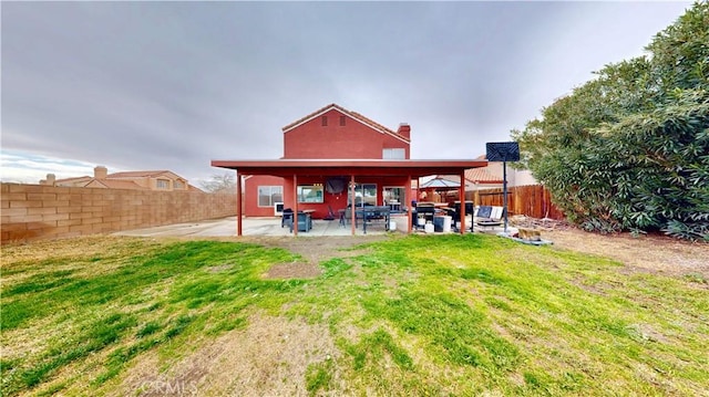 back of property with a patio, a yard, a fenced backyard, and a chimney