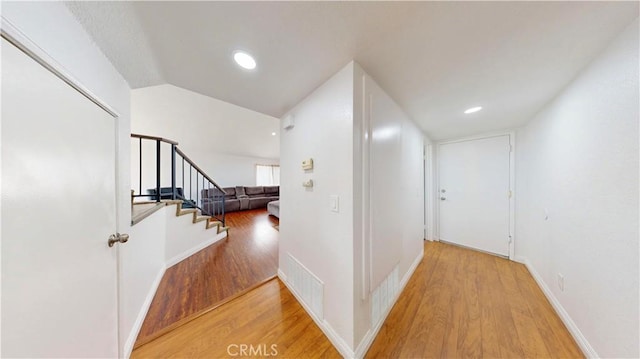 hallway with baseboards, lofted ceiling, wood finished floors, and stairs