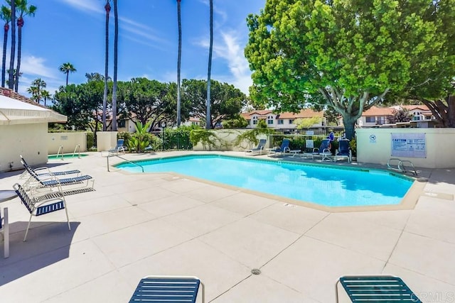 community pool with a patio and fence