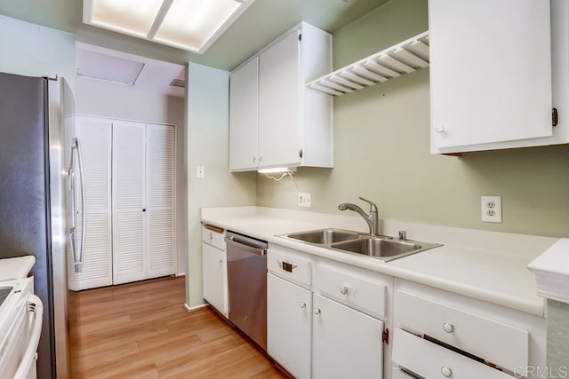 kitchen with light wood finished floors, a sink, white cabinetry, appliances with stainless steel finishes, and light countertops