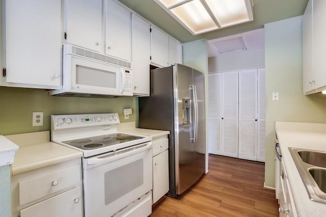 kitchen with light wood-style flooring, white appliances, white cabinets, and light countertops