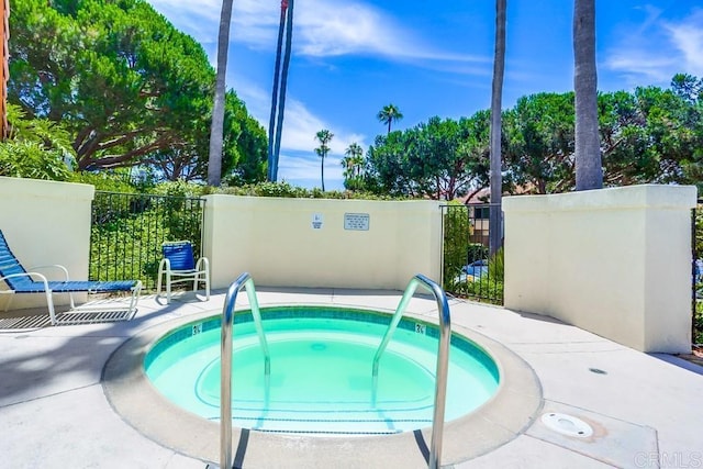 view of swimming pool with a hot tub and fence