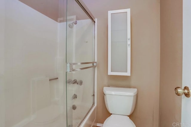 bathroom featuring toilet and combined bath / shower with glass door