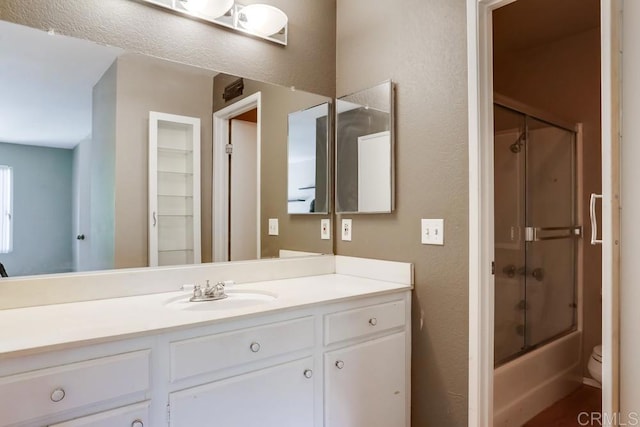 bathroom featuring enclosed tub / shower combo, toilet, and vanity