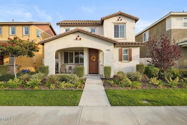 mediterranean / spanish-style house with stucco siding, covered porch, and a tile roof