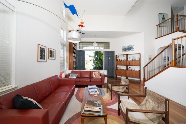 living area with stairway, a high ceiling, and wood finished floors