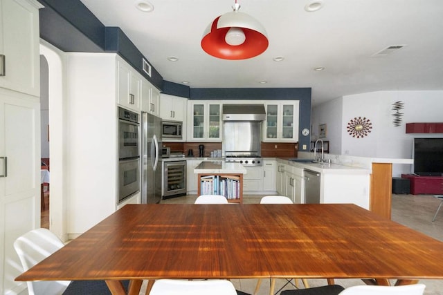 kitchen featuring visible vents, a peninsula, a sink, stainless steel appliances, and wine cooler