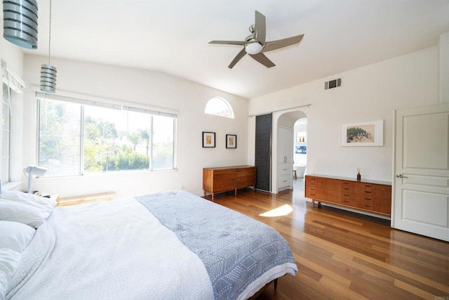 bedroom featuring a ceiling fan, wood finished floors, visible vents, and arched walkways