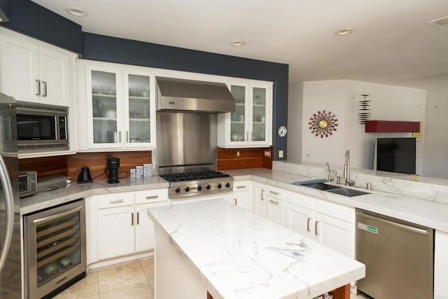 kitchen featuring light stone countertops, a sink, wine cooler, appliances with stainless steel finishes, and wall chimney range hood