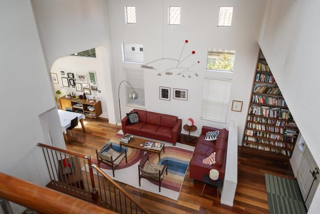 living area with arched walkways, wood finished floors, and a towering ceiling