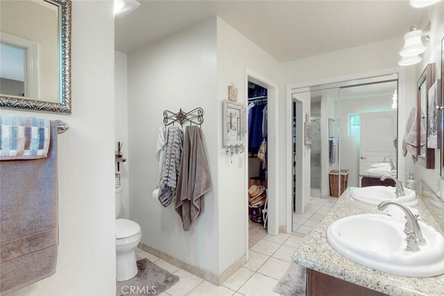 bathroom with tile patterned floors, double vanity, toilet, and a sink