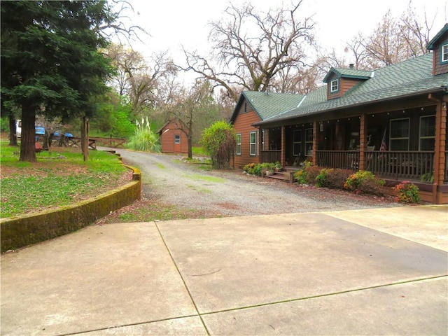 exterior space with gravel driveway, an outbuilding, and covered porch