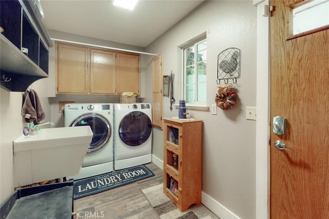 washroom with washing machine and clothes dryer, baseboards, light wood-type flooring, cabinet space, and a sink