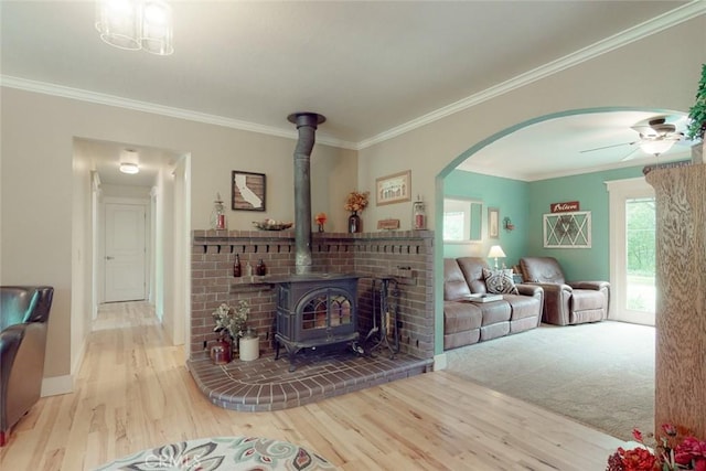 living room with wood finished floors, ornamental molding, and a wood stove