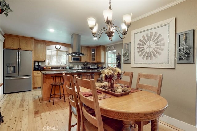 dining room featuring a healthy amount of sunlight, light wood-style floors, and ornamental molding