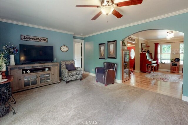 living room featuring baseboards, arched walkways, carpet floors, and ornamental molding