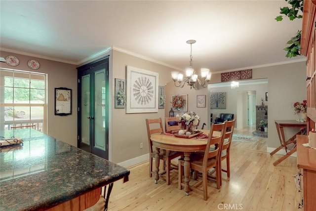 dining room with baseboards, a chandelier, crown molding, and light wood finished floors