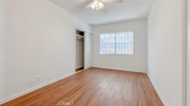 unfurnished bedroom featuring a closet, baseboards, light wood-style floors, and ceiling fan