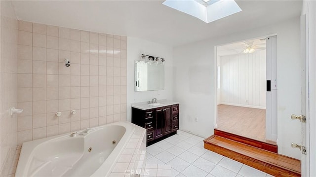 bathroom featuring vanity, a skylight, a whirlpool tub, tile patterned floors, and tile walls