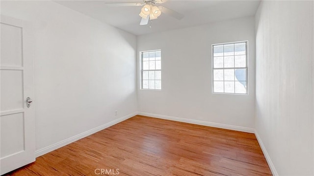 spare room featuring a ceiling fan, light wood-type flooring, and baseboards