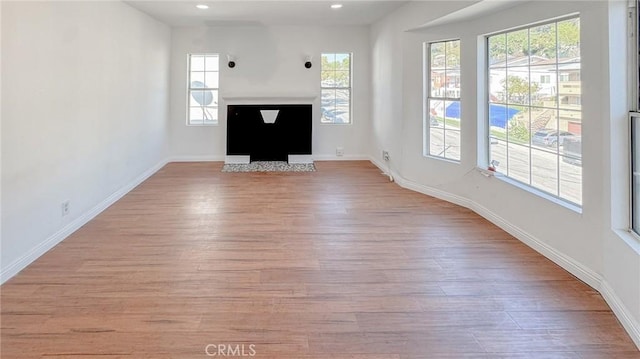 unfurnished living room with recessed lighting, wood finished floors, and baseboards