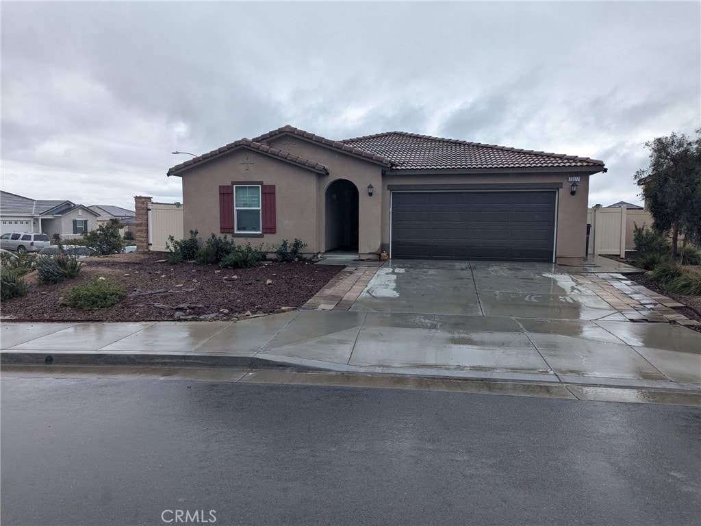 view of front of home featuring a garage, a tile roof, driveway, and stucco siding