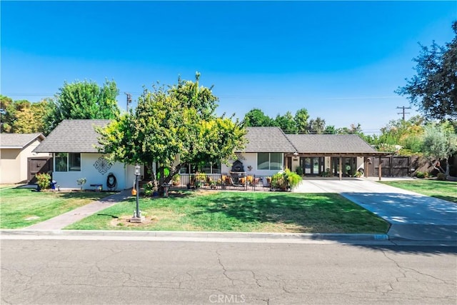 view of front facade featuring concrete driveway, a front yard, and fence