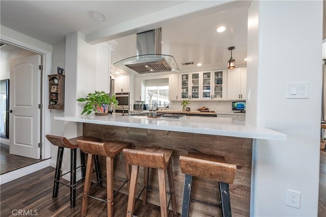 kitchen with island exhaust hood, a peninsula, a breakfast bar, and stainless steel oven