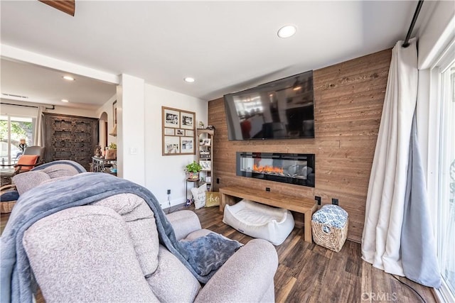 living room featuring wood finished floors, a glass covered fireplace, recessed lighting, arched walkways, and baseboards