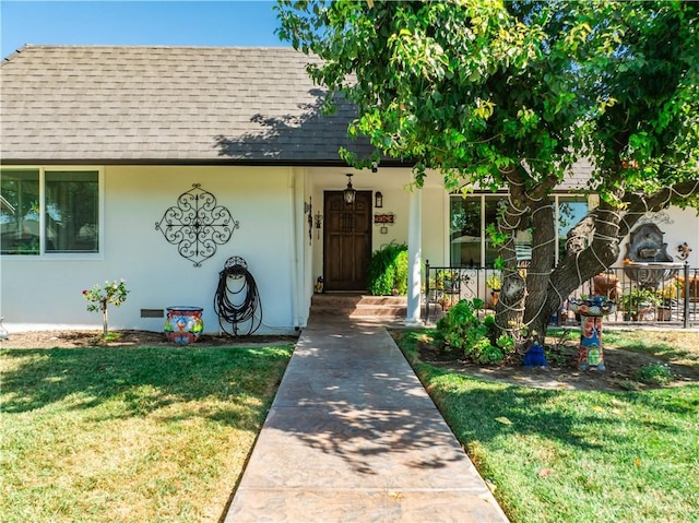 view of front of property with stucco siding, covered porch, roof with shingles, and a front lawn