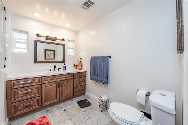 bathroom with vanity, baseboards, visible vents, tile patterned floors, and toilet