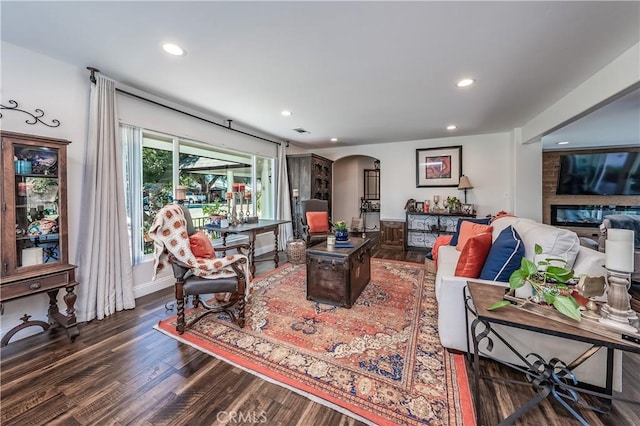 living area featuring recessed lighting, arched walkways, and wood finished floors