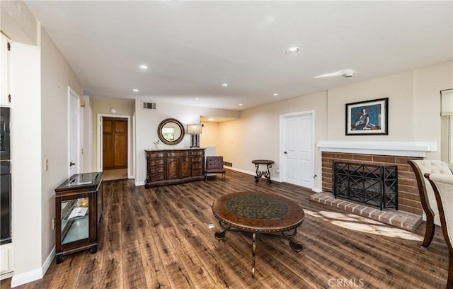 living room featuring recessed lighting, visible vents, a brick fireplace, and wood finished floors