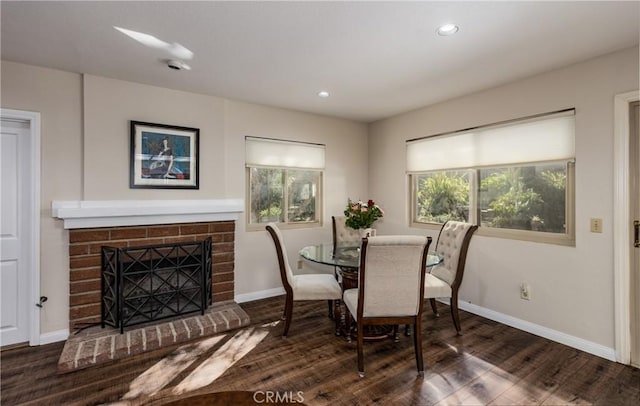 dining space with a brick fireplace, wood finished floors, baseboards, and a wealth of natural light