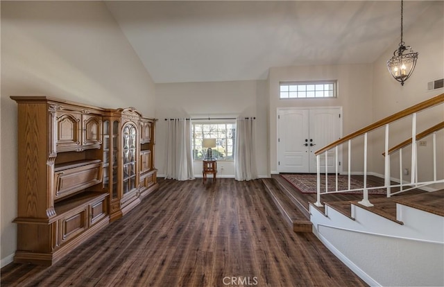 foyer entrance featuring baseboards, stairs, an inviting chandelier, high vaulted ceiling, and dark wood-style flooring