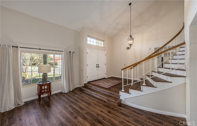 entrance foyer featuring stairway, high vaulted ceiling, baseboards, and wood finished floors