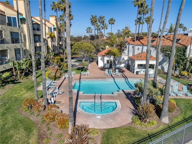 community pool with fence, a lawn, and a patio area