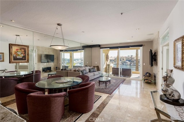 living room with a wealth of natural light, recessed lighting, a textured ceiling, and a premium fireplace