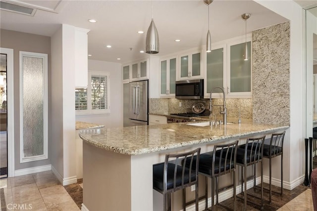 kitchen with visible vents, a sink, light stone counters, appliances with stainless steel finishes, and a peninsula