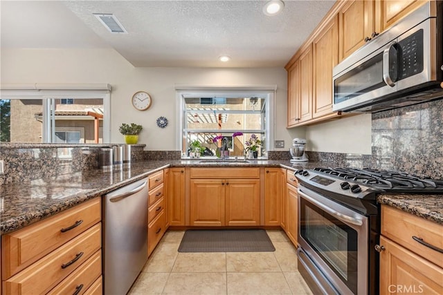 kitchen with visible vents, dark stone countertops, appliances with stainless steel finishes, and a sink