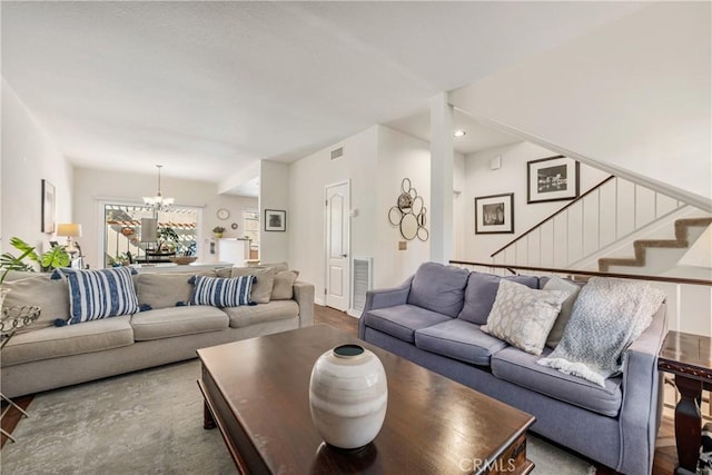 living room featuring a notable chandelier, stairs, and visible vents