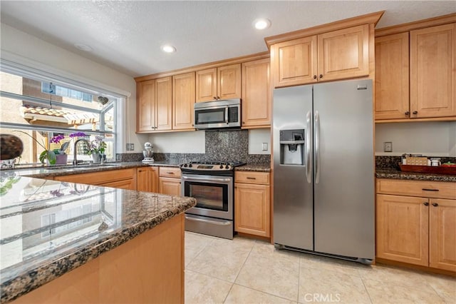 kitchen with a sink, dark stone counters, recessed lighting, and stainless steel appliances