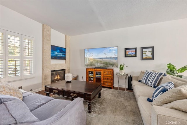 living room with wood finished floors, baseboards, and a large fireplace