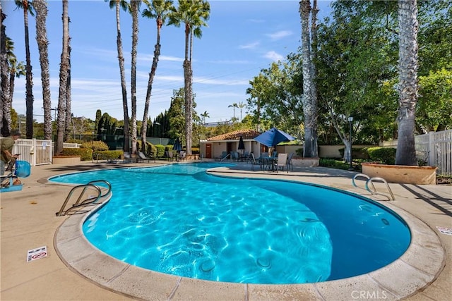 community pool with a patio area and fence