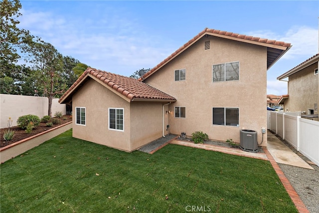 back of house with stucco siding, a lawn, a tile roof, central AC, and a fenced backyard