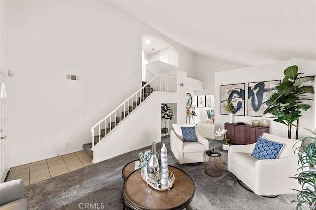 living room with tile patterned flooring, visible vents, baseboards, stairs, and high vaulted ceiling