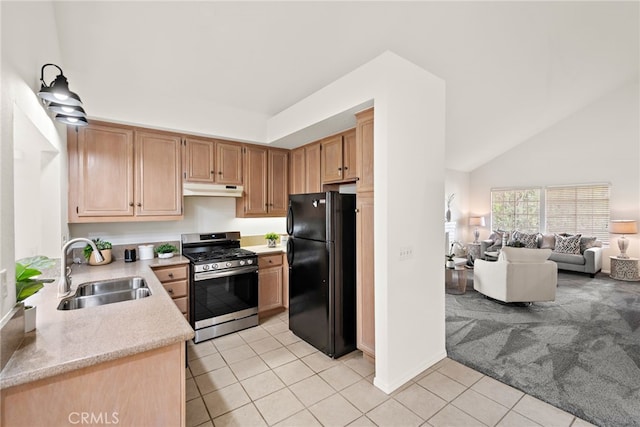 kitchen featuring freestanding refrigerator, a sink, light countertops, under cabinet range hood, and stainless steel gas stove