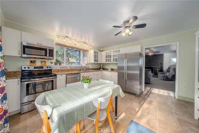 kitchen featuring a sink, ceiling fan, stainless steel appliances, white cabinets, and glass insert cabinets