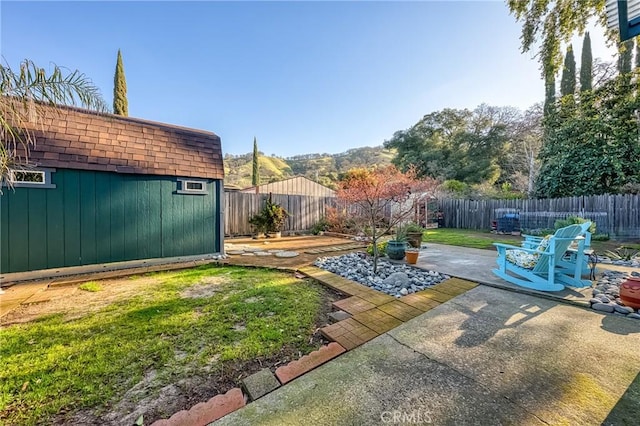 view of yard featuring a storage unit, an outdoor structure, a fenced backyard, and a patio area