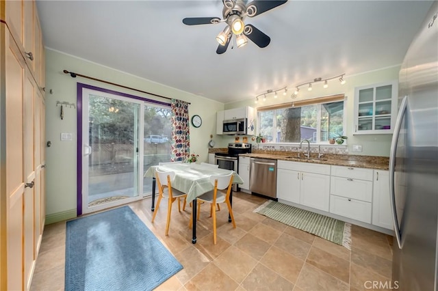 kitchen with stone counters, a sink, glass insert cabinets, appliances with stainless steel finishes, and white cabinetry